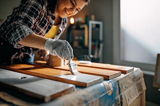 woman painting finish on wood