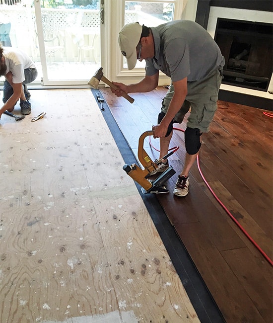 Man installing hardwood floor in living room